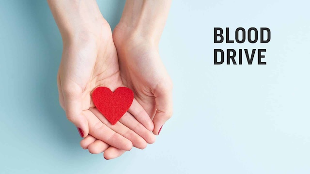 Hands holding a red heart with text reading blood drive