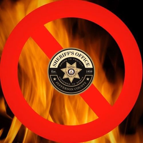 Jefferson County Sheriffs Office badge inside a banned red circle over top of flames to indicate fire ban